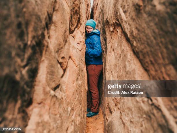young women squeezes through a slot canyon in arches national park - too small stock pictures, royalty-free photos & images