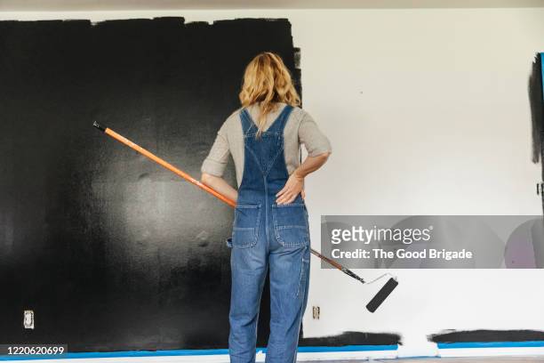 woman standing looking at painted wall at home - black interior stockfoto's en -beelden