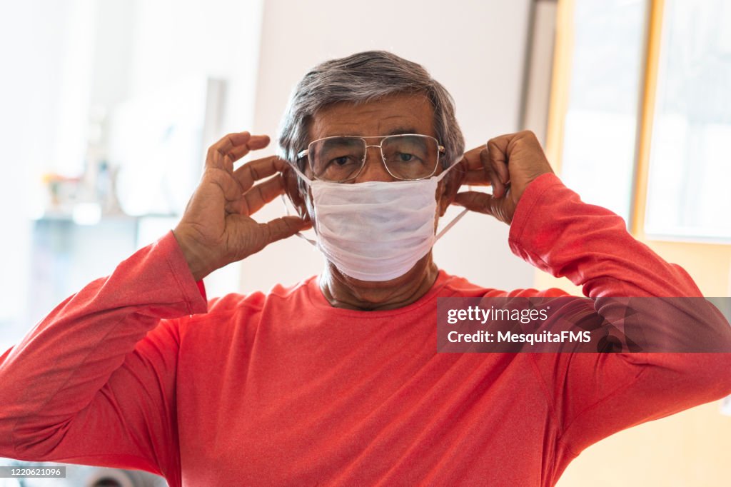 Senior man putting a protective mask on her face