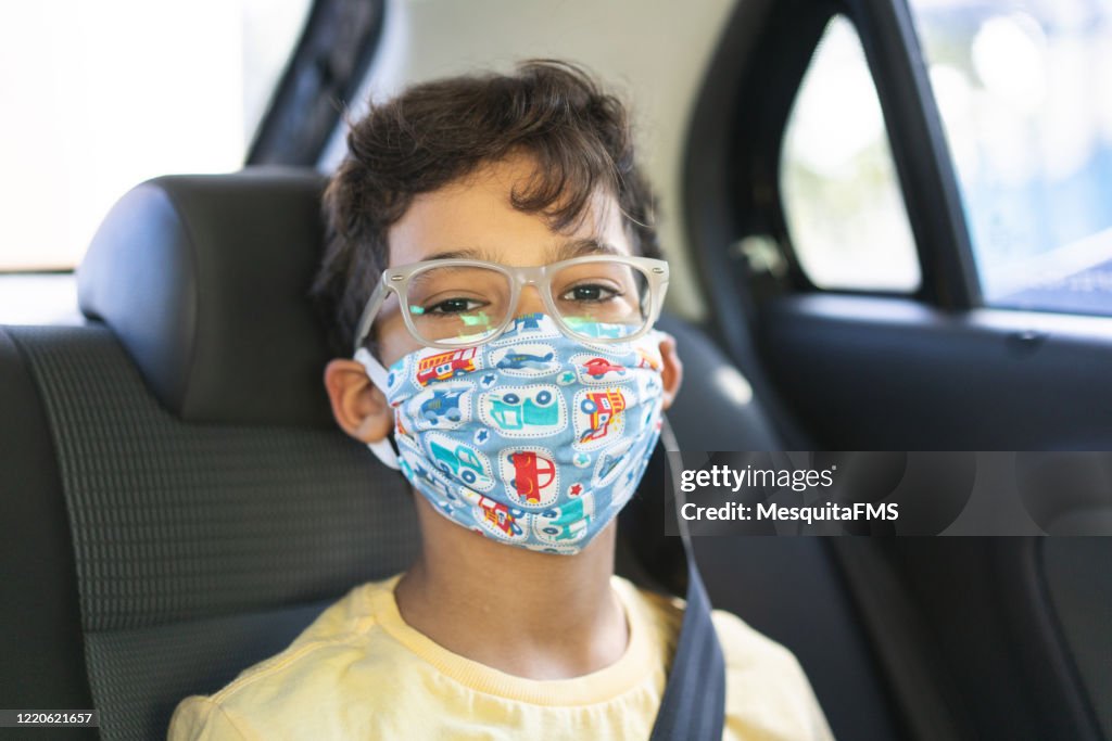 Jongen die gezichtsmasker in de achterbank van de auto draagt