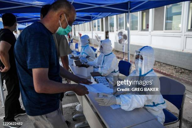 Man registers to undergo a swab test for the COVID-19 coronavirus at a testing center in Beijing on June 17, 2020. - China closed schools in Beijing...