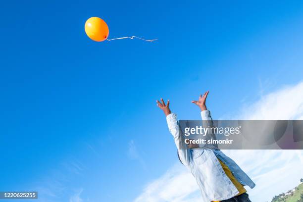 niño soltando globo en el cielo azul - releasing fotografías e imágenes de stock