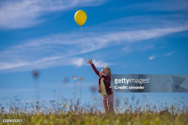 chica lanzando globo contra el cielo azul - releasing fotografías e imágenes de stock