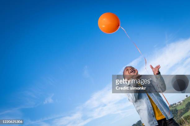 boy releasing balloon in blue sky - releasing balloons stock pictures, royalty-free photos & images