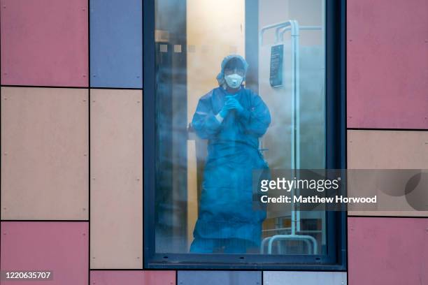 Health worker wearing PPE looks on from a window at the Royal Gwent Hospital on April 23, 2020 in Newport, United Kingdom. Following the success of...