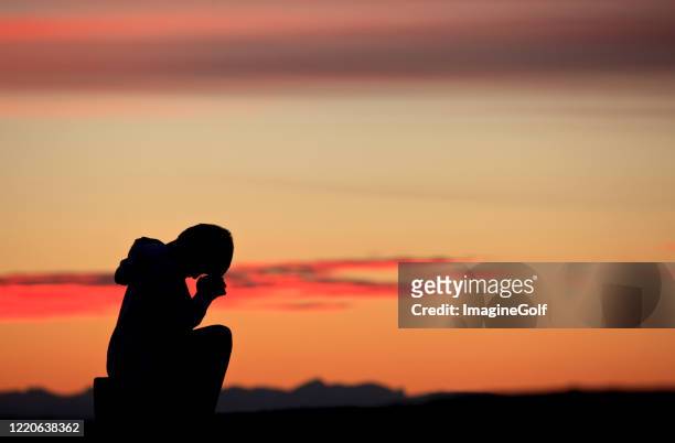 silhouette of boy praying - healing prayer images stock pictures, royalty-free photos & images