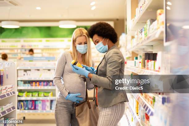 pregnant woman shopping in pharmacy house with friend during corona virus outbreak. - pharmacy mask stock pictures, royalty-free photos & images