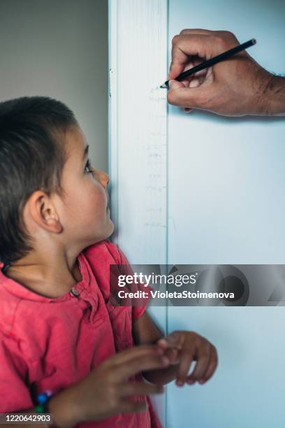 padre que mide la altura del hijo - height fotografías e imágenes de stock