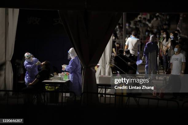 Nurse wearing a protective suit and mask takes a nucleic acid test for COVID-19 from a person who either visited or lives near the Xinfadi Market at...