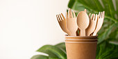bunner eco friendly disposable kitchenware utensils on white background. wooden forks and spoons in paper cup. and green leaf. ecology, zero waste concept. copyspace