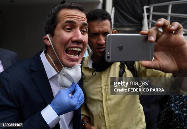 Venezuelan opposition leader and self-proclaimed acting president Juan Guaido poses for a selfie with a supporter as he leaves the headquarters of...