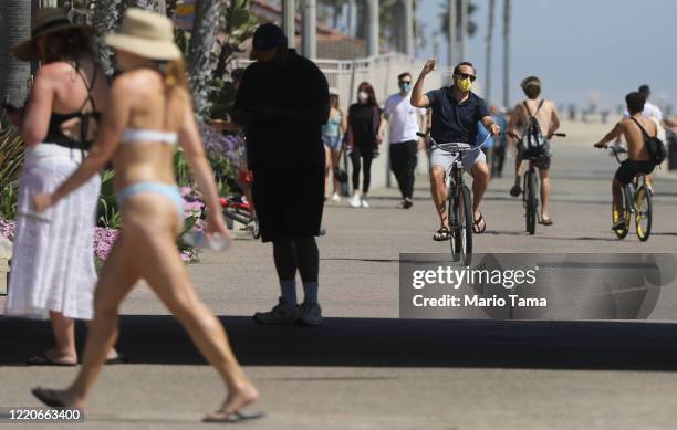 Man bikes while wearing a face mask along Huntington Beach which remains open amid the coronavirus pandemic on April 23, 2020 in Huntington Beach,...