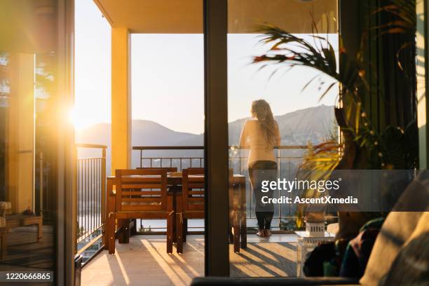 junge frau entspannt sich auf der terrasse bei sonnenaufgang - in die ferne schauen stock-fotos und bilder