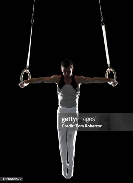 male gymnast performing iron cross on rings - male gymnast stock pictures, royalty-free photos & images