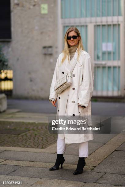 Guest wears sunglasses, a white long coat, a white woven leather padded quilted bag from Bottega Veneta, a brown turtleneck pullover, white pants,...