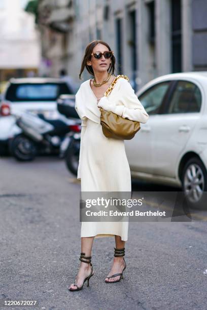 Chloe Harrouche wears sunglasses, a golden necklace, a khaki leather Bottega Veneta bag, a white dress, shoes, outside Max Mara, during Milan Fashion...