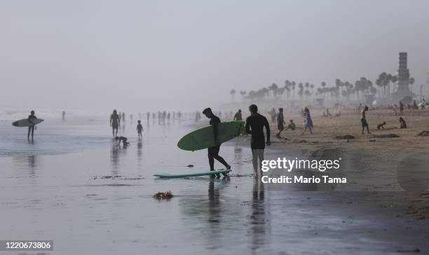 People gather on Huntington Beach which remains open amid the coronavirus pandemic on April 23, 2020 in Huntington Beach, California. Neighboring...