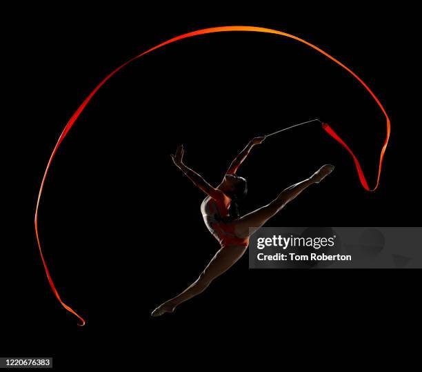 rhythmic floor gymnast leaping in the air with perfect 180 degree ribbon curve - ginnastica ritmica foto e immagini stock