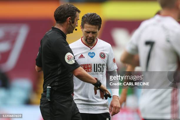 Sheffield United's English-born Northern Irish midfielder Oliver Norwood queries on the functioning of English referee Michael Oliver's watch after...