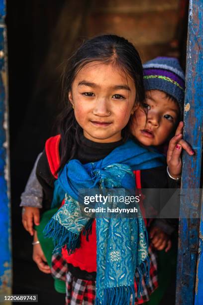 little girl carrying baby on the back, solukhumbu, nepal - nepal people stock pictures, royalty-free photos & images