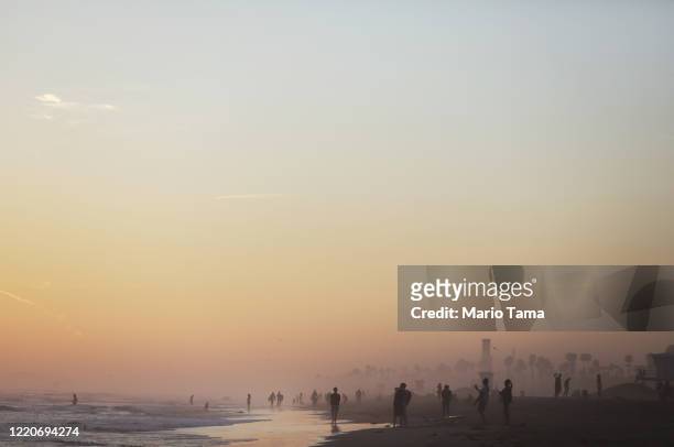 People gather on Huntington Beach, which remains open amid the coronavirus pandemic, at dusk on April 23, 2020 in Huntington Beach, California....