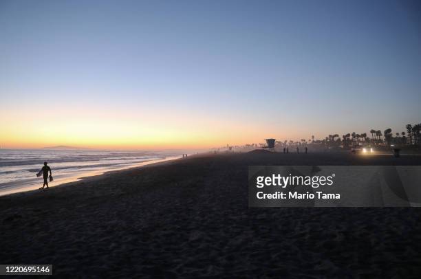 People gather on Huntington Beach, which remains open amid the coronavirus pandemic, at dusk on April 23, 2020 in Huntington Beach, California....