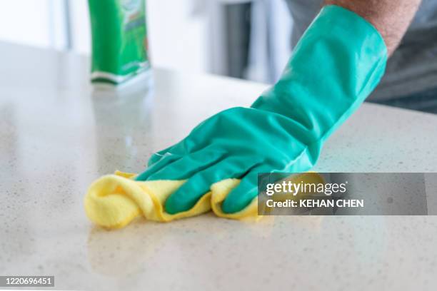 a hand wiping table surfaces - washing up glove - fotografias e filmes do acervo