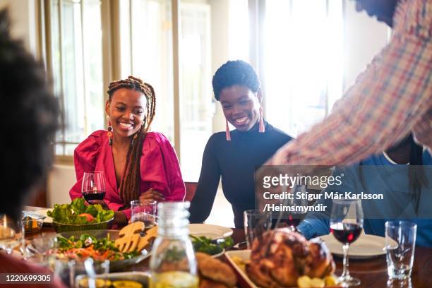 smiling women looking at men cutting turkey meat - thanksgiving day stock pictures, royalty-free photos & images