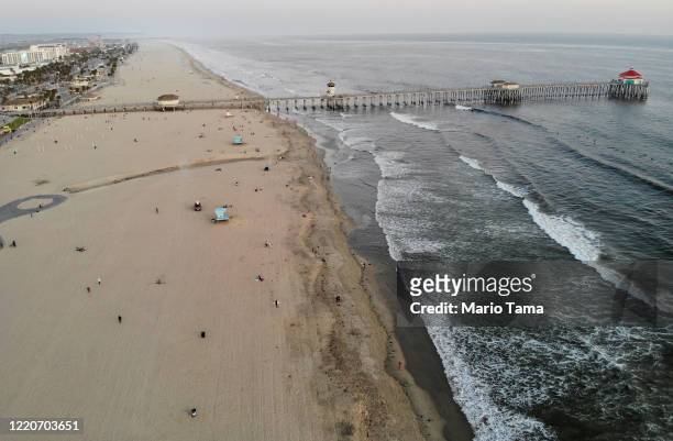 An aerial view as people gather on Huntington Beach, which remains open amid the coronavirus pandemic, at dusk on April 23, 2020 in Huntington Beach,...