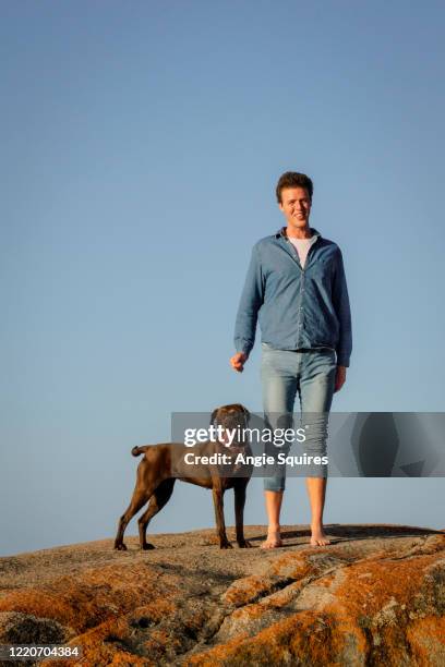 young man and labrador dog standing on top of rock - portrait lachen stock pictures, royalty-free photos & images