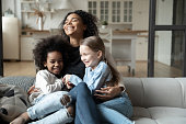 Happy biracial mom play with daughters at home
