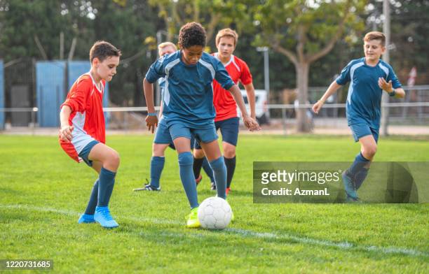 red and blue jersey boy footballers competing on field - soccer team stock pictures, royalty-free photos & images