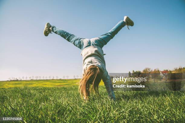 happy girl playing in handstand on summer meadow - handstand stock pictures, royalty-free photos & images