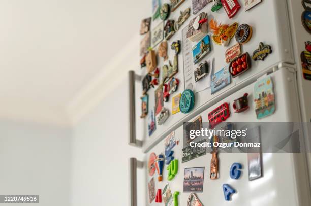 lots of various souvenir magnets on the fridge in the kitchen - fridge magnet stock pictures, royalty-free photos & images