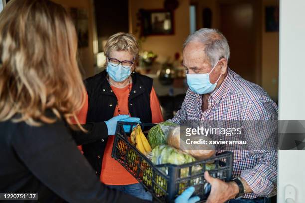 il nipote consegna generi alimentari ai nonni durante la pandemia a casa loro - sostegno morale foto e immagini stock