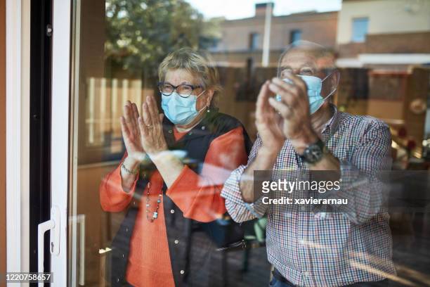 senior couple on their 70s clapping hands at home in quarantine covid-19 - clapping stock pictures, royalty-free photos & images