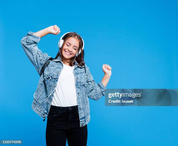 fröhliche gymnasiastin hört musik - jeansjacke stock-fotos und bilder