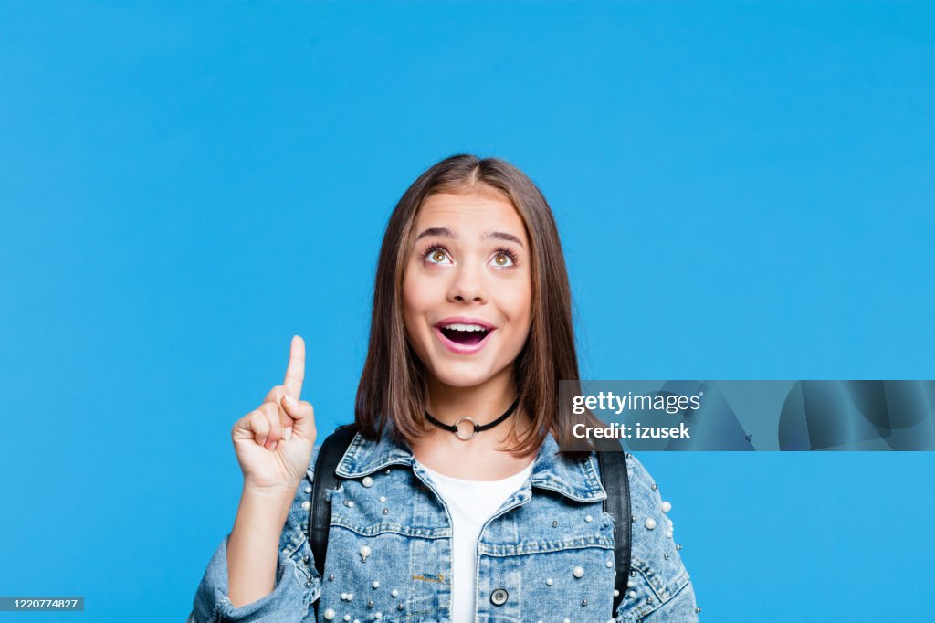 Happy teenge girl pointing with finger at copy space