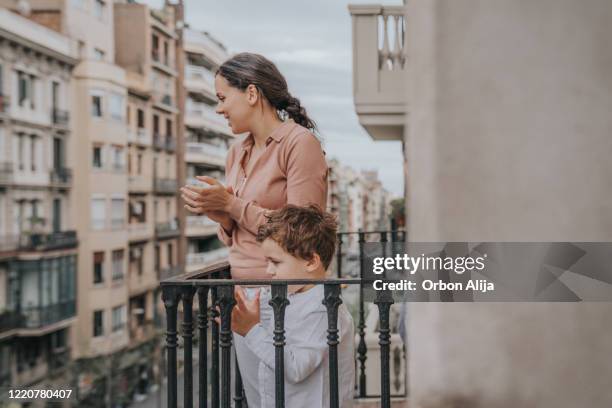 family applauding to the medical staff from the balcony for covid-19 - spain coronavirus stock pictures, royalty-free photos & images