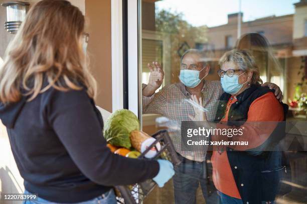 granddaughter delivers groceries to grandparents during pandemic - family lockdown stock pictures, royalty-free photos & images