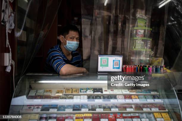 The owner wear a mask while sitting in the shop on April 24, 2020 in Wuhan, Hubei Province, China.the government started lifting outbound travel...