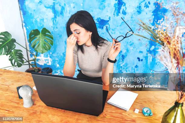 tired girl working at a table with a computer. - zona horaria fotografías e imágenes de stock