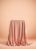 Presentation pedestal with pink silk cloth on a pink background. Isolated with clipping path.