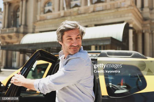 mature businessman disembarking taxi - car leaving stock pictures, royalty-free photos & images