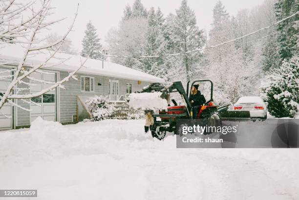 young woman clearing snow using tractor - plow driveway stock pictures, royalty-free photos & images