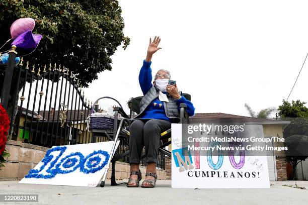 Mary Fierros waves at the line of cars driving by her home during a parade celebrating her 100 birthday in San Jose, Calif., on Monday, April 20,...