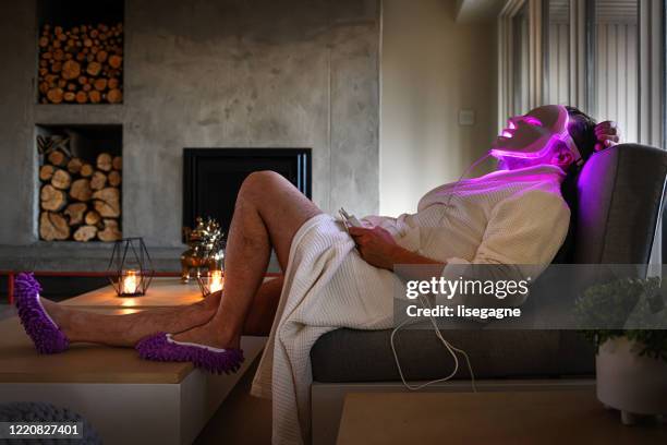 uomo maturo che fa una terapia della luce di notte - luce led foto e immagini stock