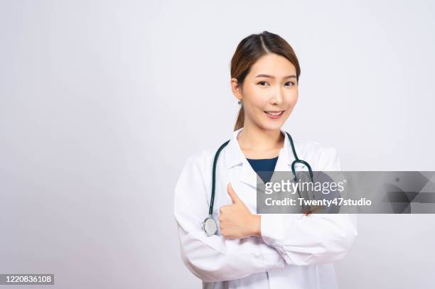 young asian doctor wearing white doctor wear standing on white background - psychiatric hospital stockfoto's en -beelden