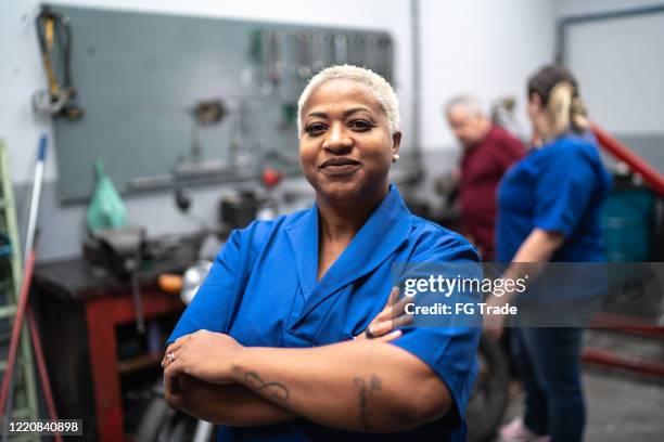 portrait of smiling woman with arms crossed in auto repair - blue collar portrait stock pictures, royalty-free photos & images