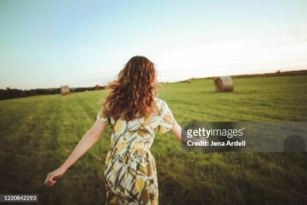 woman running in field, woman's back, rear view - man running away stock-fotos und bilder